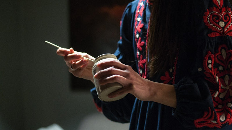 Mâini de femeie ținând borcan ceramic Apiarium cu Tonic apicol și linguriță cu doza zilnică, ritual de îngrijire a sinelui și prevenție a burnout-ului