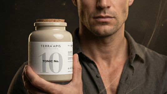 Man in a dark shirt presenting a beige bottle labeled Terra Apis Tonic No. 10 toward the camera.